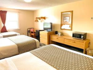 a hotel room with two beds and a television at Sandusky Inn in Sandusky
