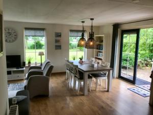 a dining room and living room with a table and chairs at Vakantiehuis Tzummarum in Tzummarum