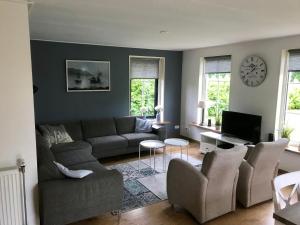 a living room with a couch and chairs and a clock at Vakantiehuis Tzummarum in Tzummarum