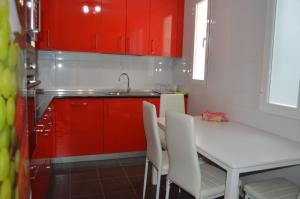 une cuisine avec des placards rouges, une table blanche et des chaises dans l'établissement VUT Collado 28 Segundo, à Soria