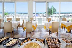un restaurante con mesas y sillas con comida a la vista en Hotel Orizzonte en Bellaria-Igea Marina