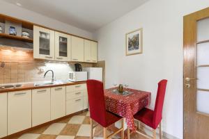 una cocina con mesa con sillas rojas y fregadero en Apartment Pegy, en Zadar