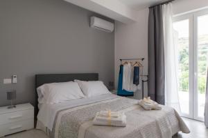 Un dormitorio blanco con una cama con toallas. en House 103 Rent Apartment, en Capo dʼOrlando