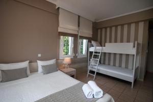 a bedroom with two beds and a bunk bed and a ladder at Nostos Hotel in Afitos