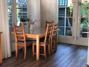 una mesa de comedor con sillas y un jarrón con flores en De Bonte Specht en Nijverdal