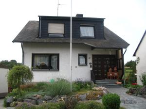 een wit huis met een zwart dak bij Ferienwohnung Am Frankenbach in Franken
