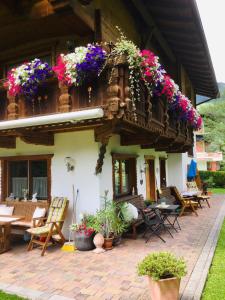 un patio con mesas, sillas y flores en un edificio en Haus Marco, en Neustift im Stubaital