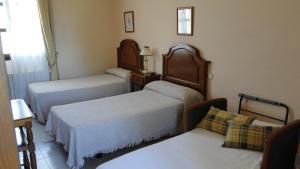 a hotel room with two beds and a couch at Hostal Las Paneras in Ávila