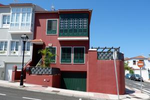 ein rotes Gebäude mit grünen Rollläden auf einer Straße in der Unterkunft La Orotava vacational rental home in La Orotava