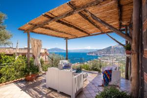 a patio with chairs and a pergola overlooking the water at Villa Antonella in Sorrento