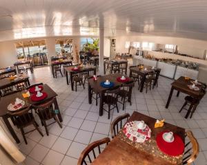 タマンダレーにあるApart Hotel Tamandaréのテーブルと椅子が備わる空きレストランとキッチンがあります。
