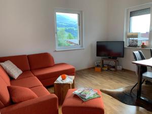 sala de estar con sofá rojo y TV en Alpenblick, en Aich