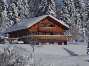 une cabane en rondins dans la neige avec des arbres enneigés dans l'établissement Les Genévriers, à Foncine-le-Haut