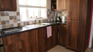 a kitchen with wooden cabinets and a sink and a window at No 9 Seanachaí Holiday Homes Holiday home in Dungarvan