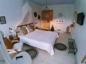 a bedroom with a large white bed and a chair at Summer House Moschovi in Skala Potamias