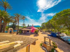 a resort with palm trees and a pink building at Can Cap de Bou by Alquilair in Pollença