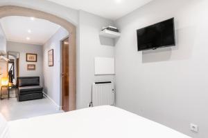 ein Schlafzimmer mit einem Bett und einem TV an der Wand in der Unterkunft Brand new and perfect location: historic center in Lissabon