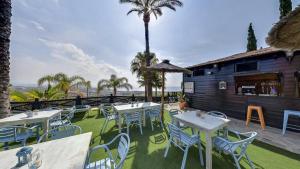 Un restaurante con mesas y sillas y una palmera. en Apartamentos Manilva Green, en Manilva