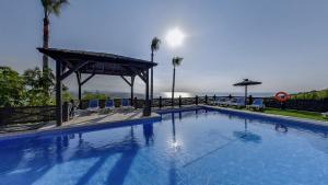 Una gran piscina azul con un cenador en Apartamentos Manilva Green, en Manilva