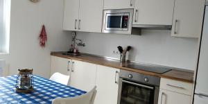 kuchnia z białymi szafkami, stołem i kuchenką mikrofalową w obiekcie ITXASO w mieście Hondarribia