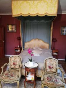 a bedroom with a bed with two chairs and a table at Château de la Bucaille - entier in Aincourt
