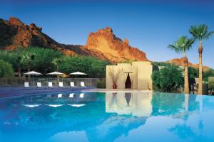 a swimming pool with chairs and a building with a mountain at Sanctuary Camelback Mountain, A Gurney's Resort and Spa in Scottsdale