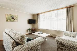 a living room with two chairs and a table and a window at Coromandel Cottages in Coromandel Town