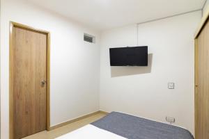 a bedroom with a bed and a tv on the wall at Ayenda Casa Megua in Medellín +10 photos