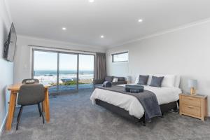 um quarto com uma cama, uma escrivaninha e uma janela em Kaka Point Views Apartment 2 em Kaka Point