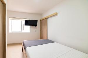 a bedroom with a bed and a tv on a wall at Ayenda Casa Megua in Medellín