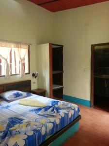 a bedroom with a bed with a blue and white comforter at Hostal Nova Colonial in Puerto Colombia
