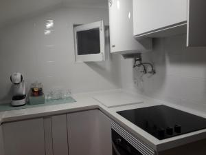 uma cozinha com um lavatório preto e armários brancos em Sesimbra Beach Fonte House em Sesimbra mais 4 fotografias