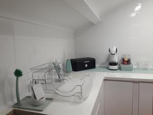 eine weiße Küche mit einem Geschirrregal und einem Waschbecken in der Unterkunft Sesimbra Beach Fonte House in Sesimbra