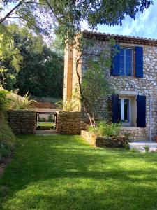 a stone house with blue windows and a yard at XIXe Provencal Stone House with Private Pool near Uzes in Uzès