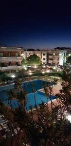 a swimming pool at night with buildings in the background at Taormina Mare Piscina Fondachello in Fondachello