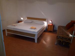 een slaapkamer met een wit bed en een stoel bij Apartments Anđelka in Pag