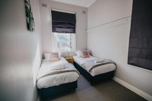 two twin beds in a small room with a window at Duke of Wellington Hotel in New Lambton