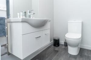 a white bathroom with a sink and a toilet at Kaka Point Views Apartment 1 in Kaka Point