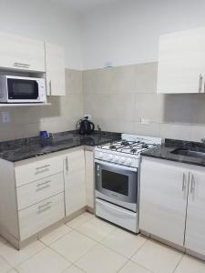 a kitchen with white cabinets and a stove top oven at Apart Ocampo Catamarca in San Fernando del Valle de Catamarca