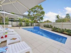 una piscina con sedie a sdraio bianche e una piscina di Oceans Eleven at Iluka Resort Apartments a Palm Beach