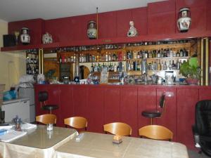 un restaurante con un bar con paredes y sillas rojas en Miramare Hotel, en Lakkíon