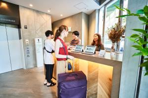 een groep mensen die aan een toonbank in een winkel staan bij &AND HOSTEL HOMMACHI EAST in Osaka