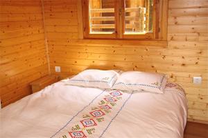 a bed in a wooden cabin with two pillows at Camping Abadesses in Sant Joan de les Abadesses