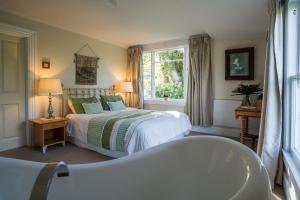 Schlafzimmer mit einem Bett, einer Badewanne und einem Fenster in der Unterkunft Theatre Royal Hotel in Kumara