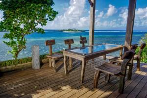 a wooden deck with a table and chairs on the ocean at Naya Matahora Island Resort in Longga