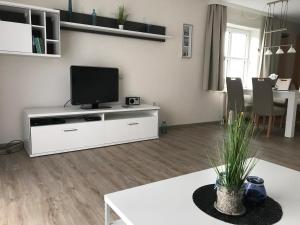 - un salon avec un centre de divertissement blanc et une télévision dans l'établissement Steiner Strandappartements Appartement 110 Südseite mit seitlichem Meerblick, à Stein