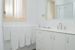 a white bathroom with white towels and a sink at Sportsmans Motor Inn in Barooga