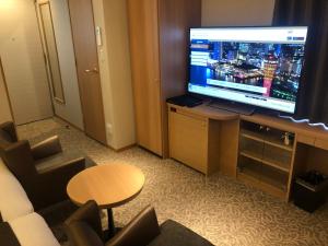 ein Wohnzimmer mit einem großen TV in einem Hotelzimmer in der Unterkunft Kobe Luminous Hotel Sannomiya in Kōbe