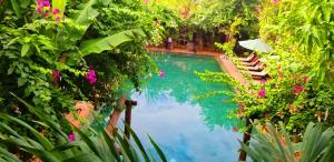 uma piscina rodeada de plantas e flores em La Niche D'angkor Boutique Hotel em Siem Reap