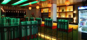 a bar with green chairs in a room at MIO Hotel in Quy Nhon